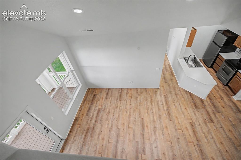 Image 16 of 23: Open-concept room featuring wood-finish flooring, a kitchen area with dark 