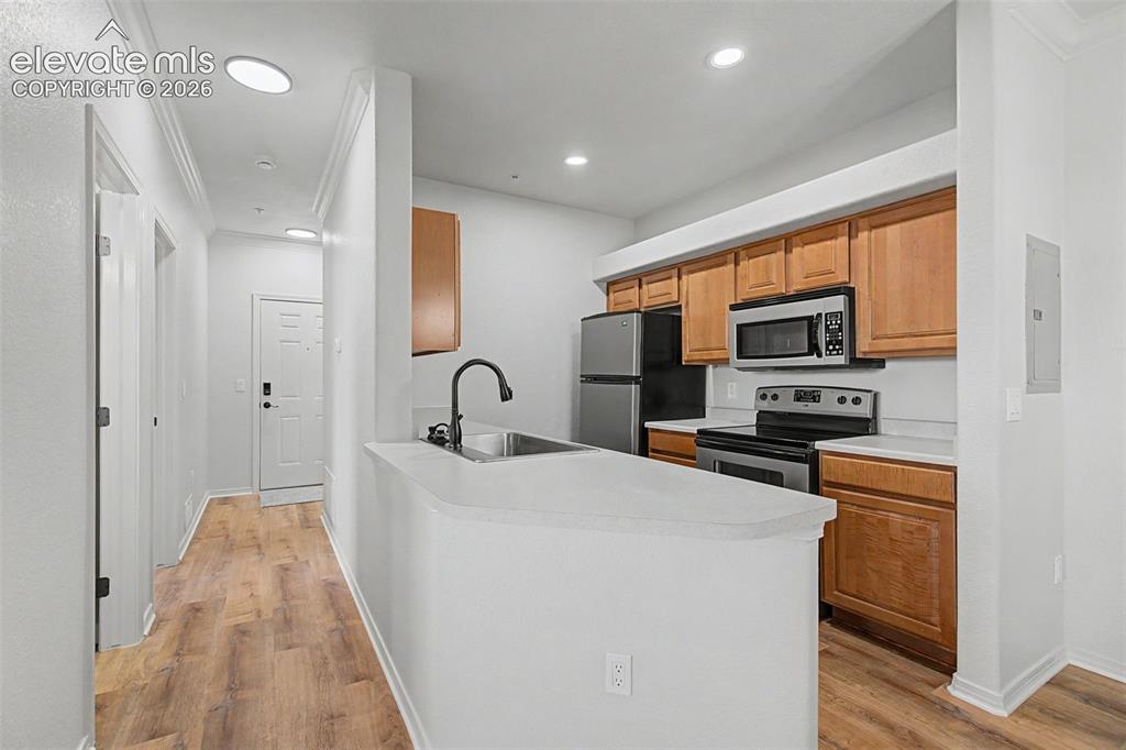 Image 7 of 23: Light wood cabinetry, solid-surface countertops, and stainless steel applia