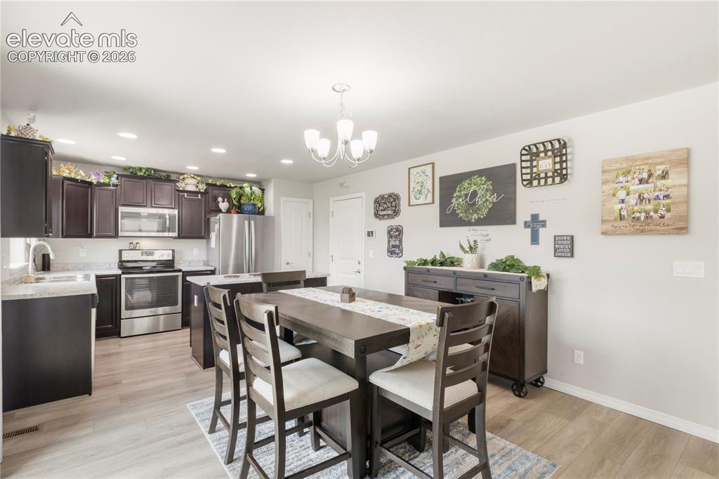 Image 11 of 38: Kitchen featuring wood-finish flooring, dark wood cabinetry, light-toned co
