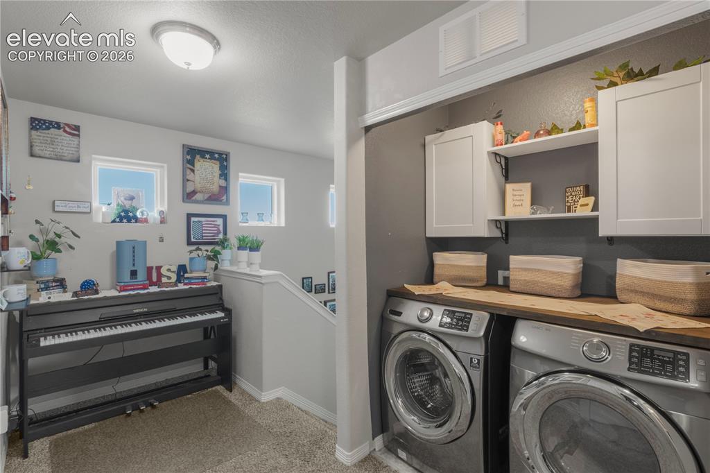 Image 17 of 38: Dedicated laundry area featuring white cabinetry, an integrated shelf, and 