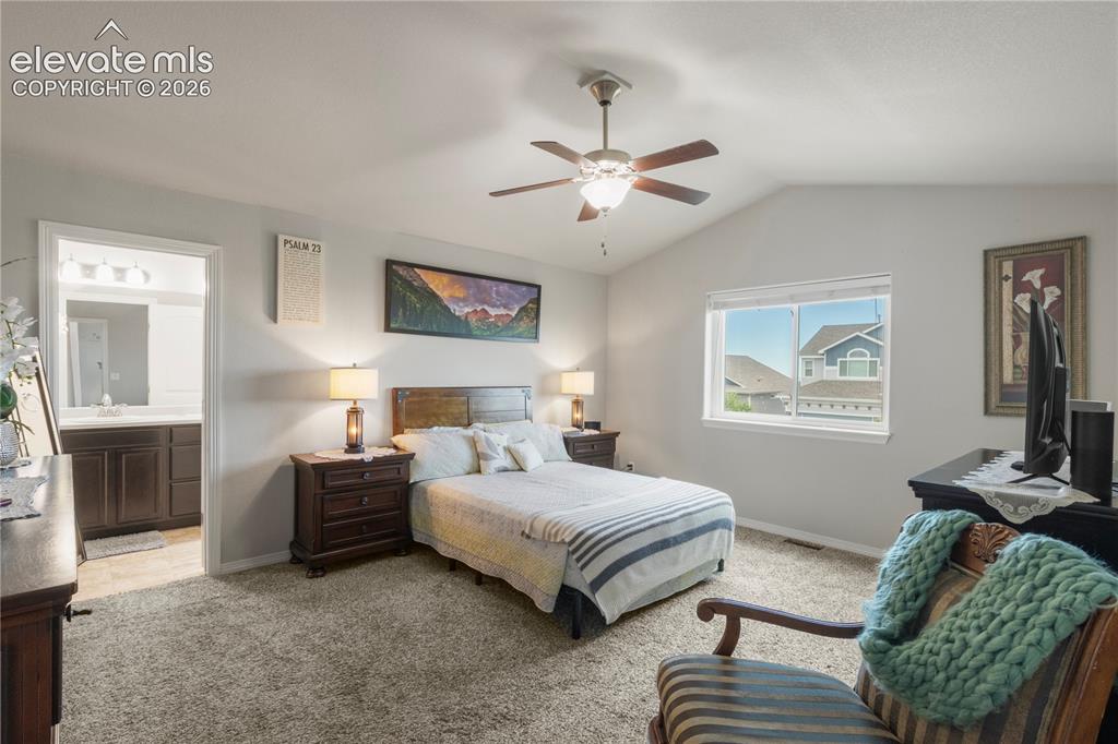 Image 18 of 38: Vaulted ceiling with ceiling fan, large window, and broadloom carpeting