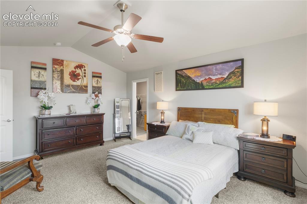 Image 19 of 38: Vaulted ceiling, ceiling fan, carpet flooring, and a doorway leading to an 