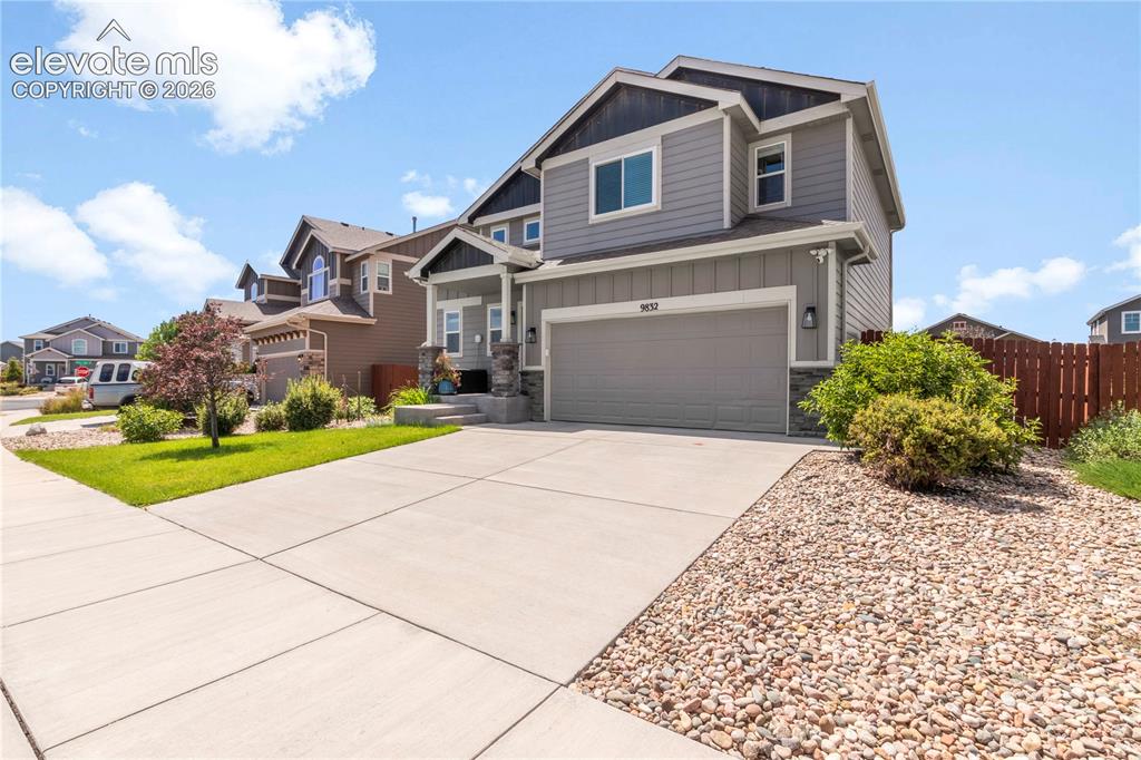 Image 2 of 38: Two-story residence featuring grey siding, an attached garage, and a covere