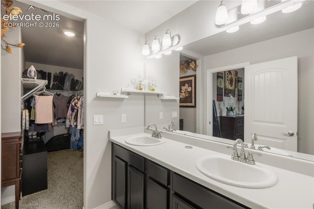 Image 23 of 38: Dual vanity with white countertop, chrome faucets, and dark wood-finish cab