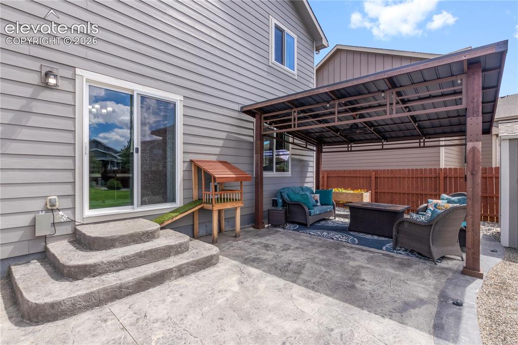 Image 31 of 38: Expansive stamped concrete patio featuring a covered pergola, sliding glass