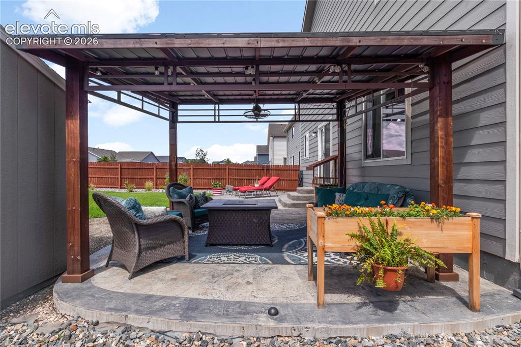 Image 32 of 38: Outdoor patio with a wood-framed pergola, stamped concrete base, and integr
