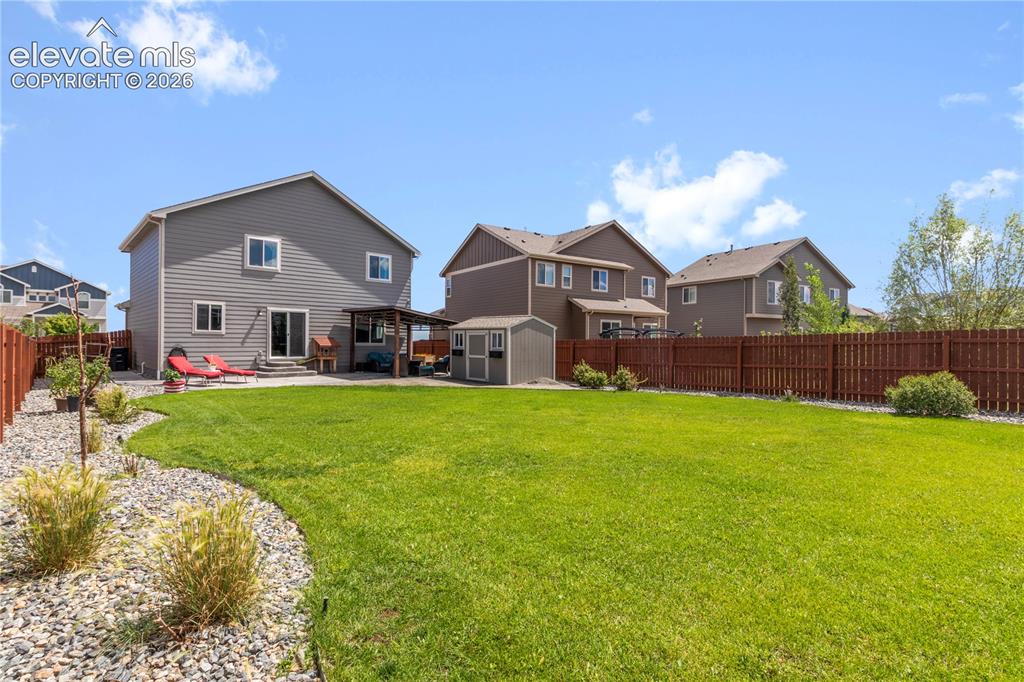 Image 35 of 38: Expansive backyard featuring a manicured lawn, established landscaping, and