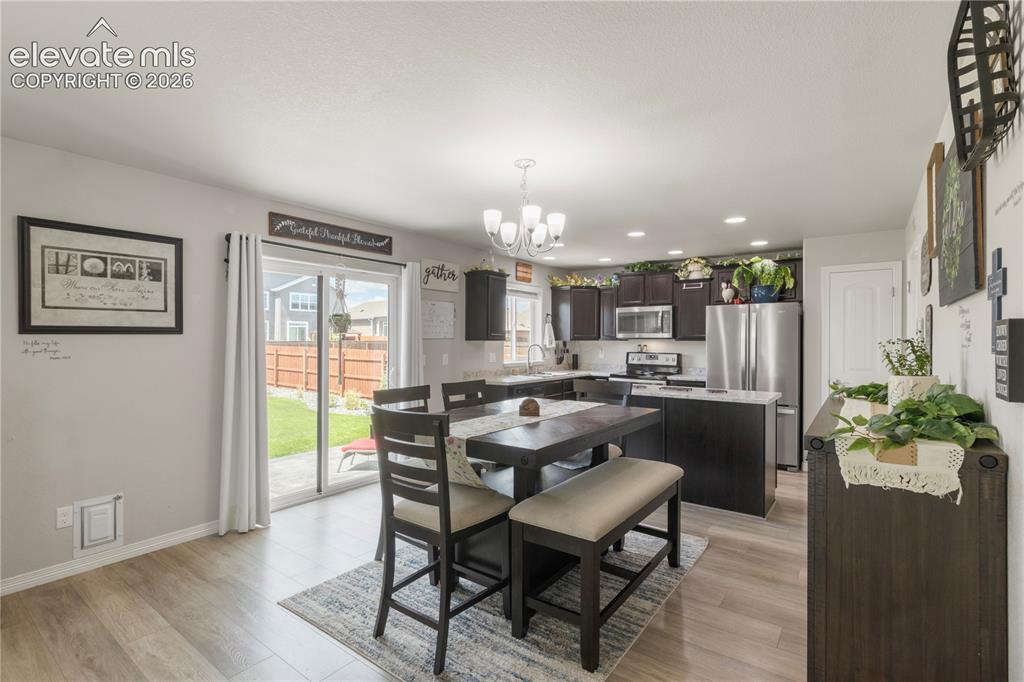 Image 9 of 38: Kitchen featuring wood-finish flooring, dark wood-finish cabinetry, stainle