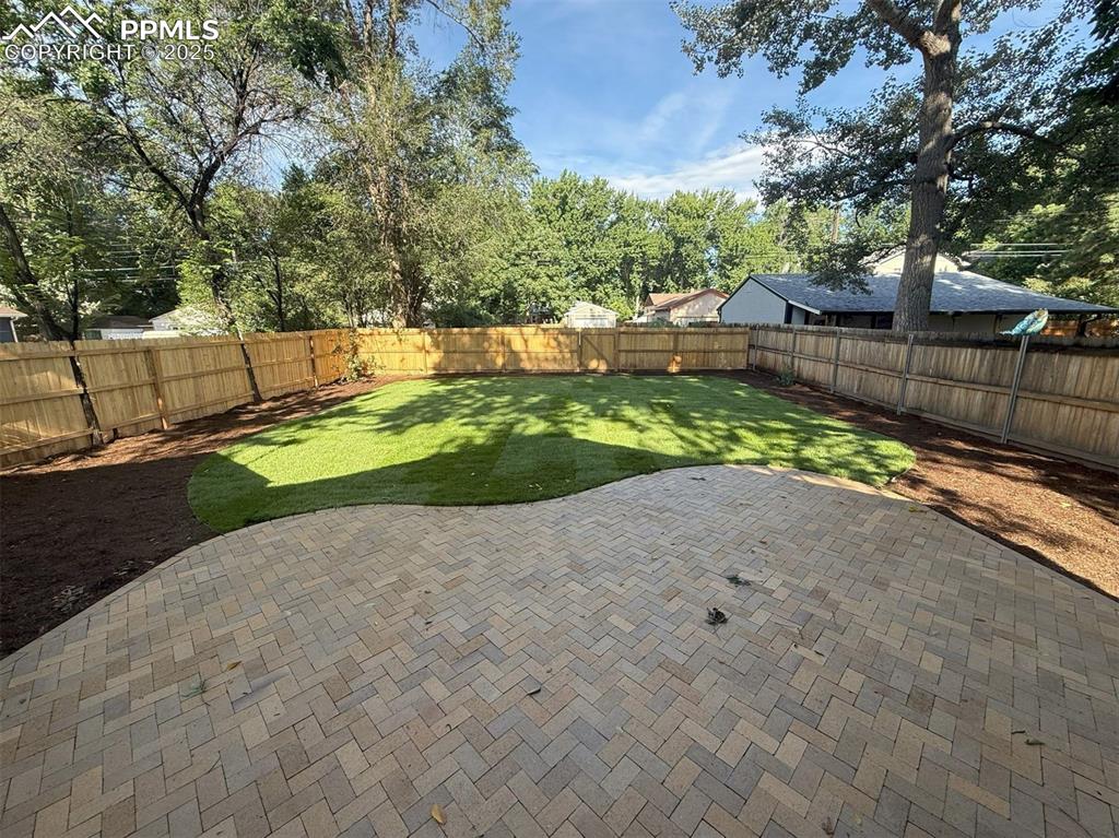 Image 35 of 39: Fully fenced backyard with new brick patio.