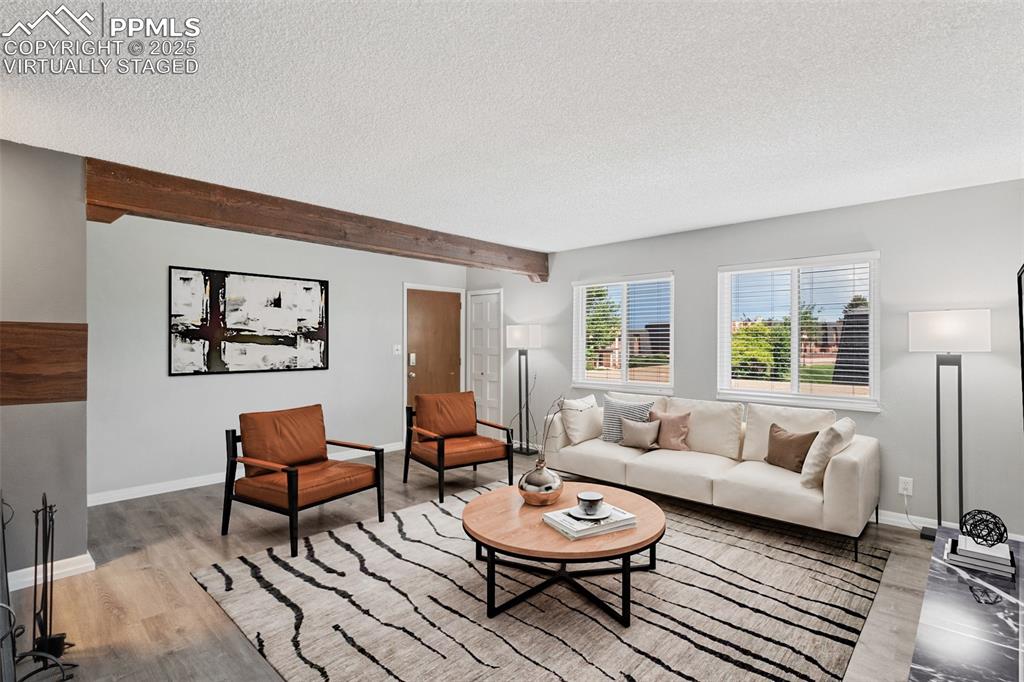 Image 10 of 48: Virtually Staged - Living area with a textured ceiling, wood finished floor