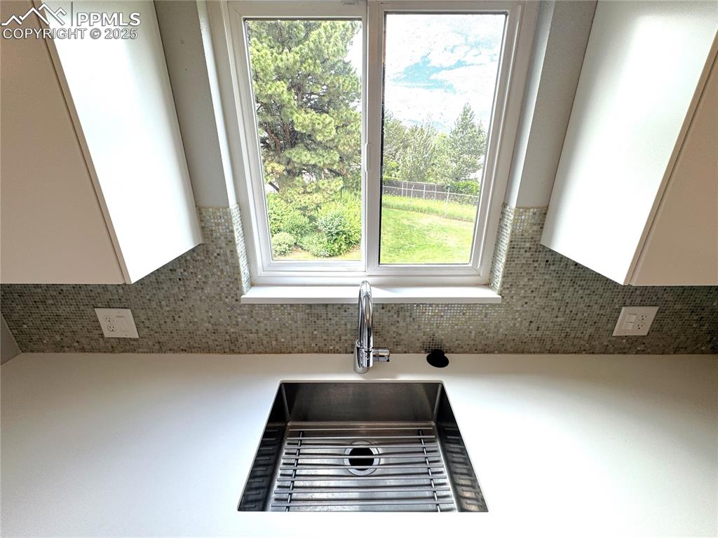 Image 16 of 48: Kitchen view of white cabinets, decorative backsplash, and light countertop