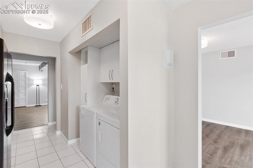 Image 18 of 48: Laundry area with independent washer and dryer, cabinet space, and light ti
