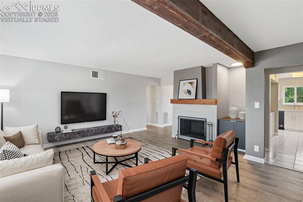Image 6 of 48: Virtually Staged - Living room featuring wood finished floors, a textured c