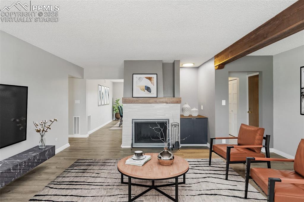 Image 9 of 48: Virtually Staged - Living room featuring a fireplace, wood finished floors,