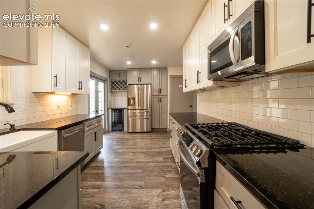 Image 10 of 33: Open-concept kitchen featuring wood-finish flooring, white subway tile back