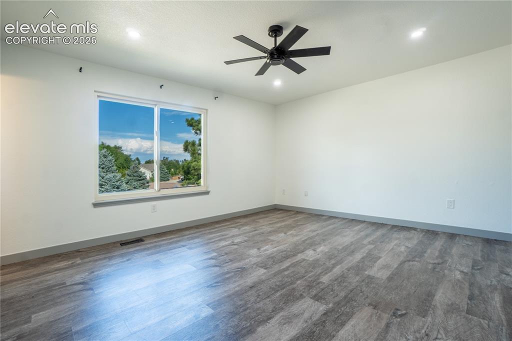 Image 13 of 33: Spacious room featuring wood-finish flooring, white walls, and a large wind