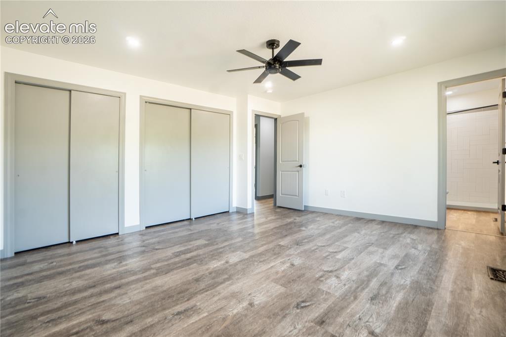 Image 14 of 33: Spacious room featuring wood-finish flooring, two sets of double sliding cl