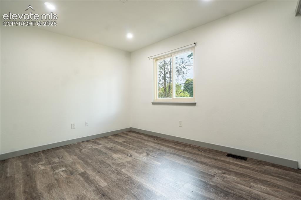 Image 16 of 33: Bright room featuring a window with a white frame, wood-finish flooring, re