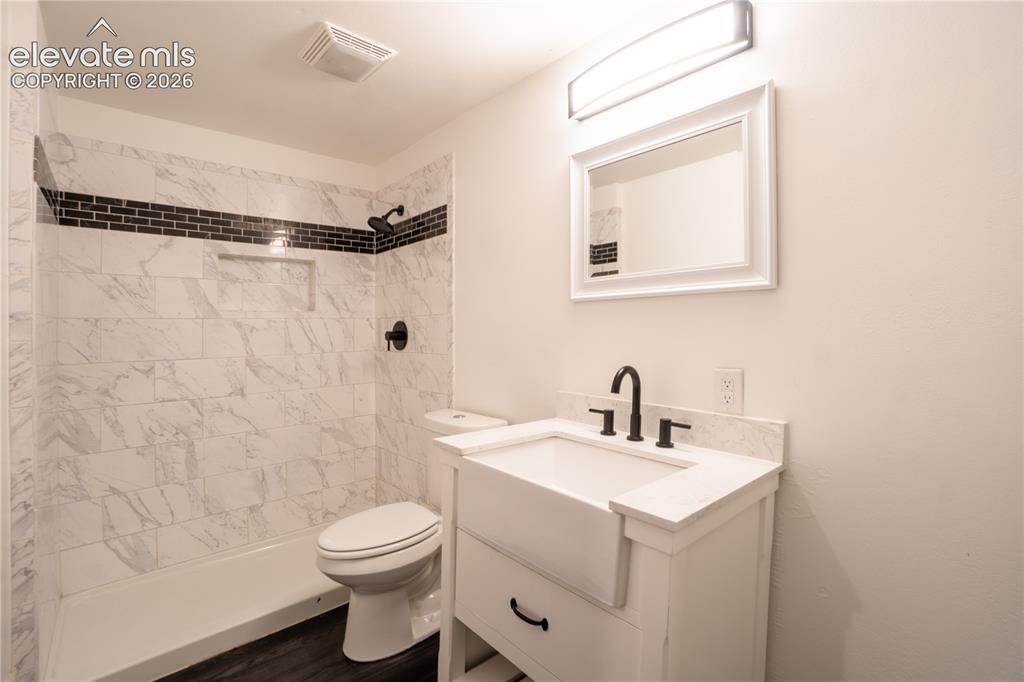 Image 25 of 33: Bathroom featuring a white vanity with an integrated sink, dark wood-finish