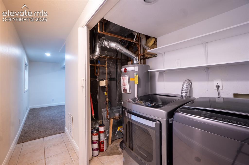Image 26 of 33: Dedicated utility area featuring a water heater and integrated shelving