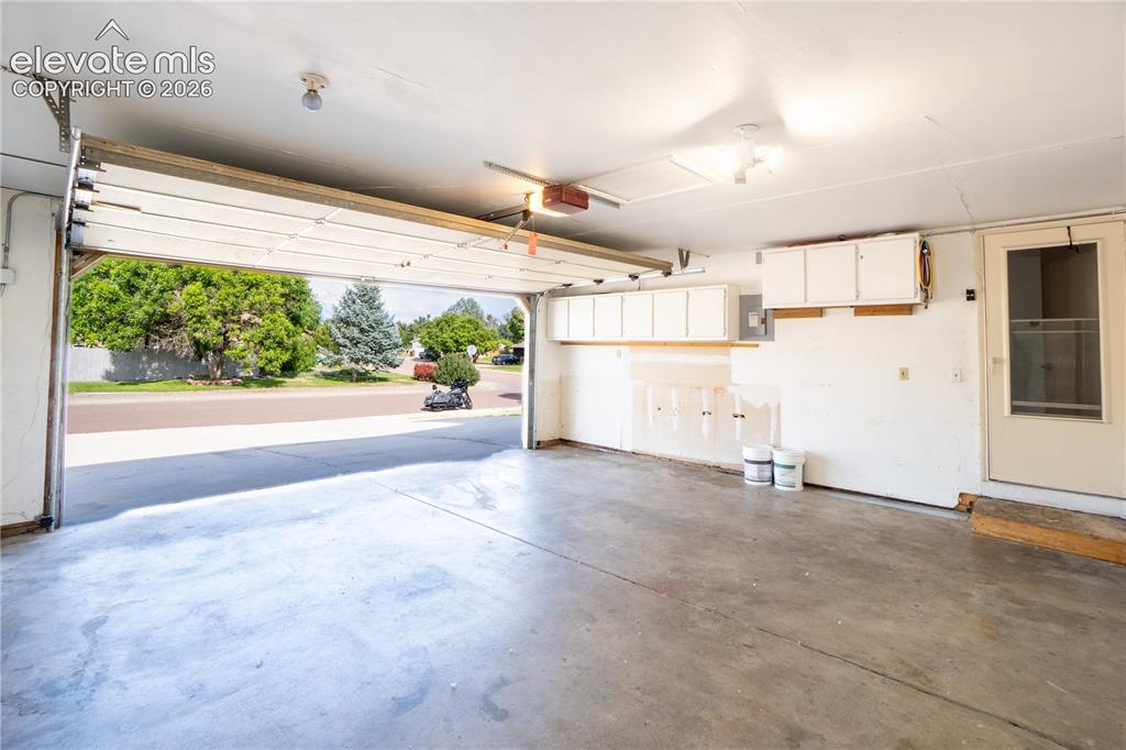 Image 27 of 33: Spacious garage featuring a concrete floor, overhead lighting, and built-in