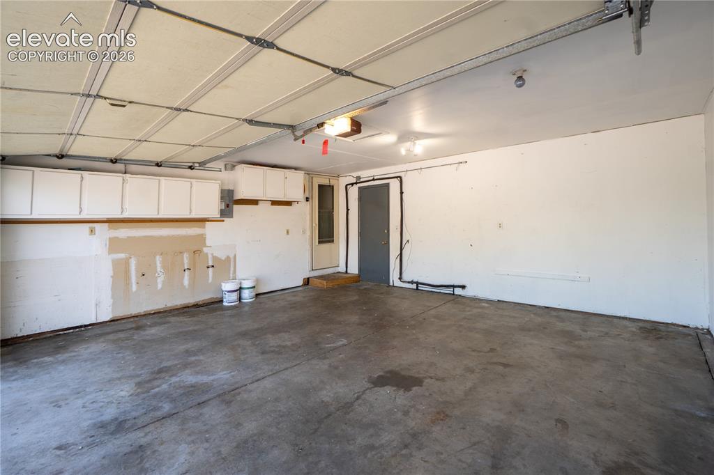 Image 28 of 33: Spacious garage featuring concrete flooring and exposed ceiling supports