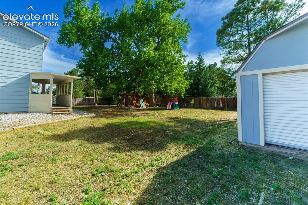 Image 29 of 33: Spacious backyard featuring a substantial mature tree, partial privacy fenc