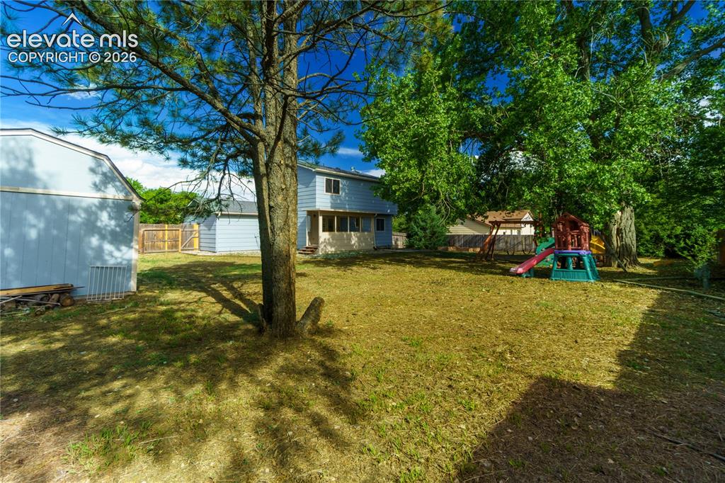 Image 30 of 33: Spacious backyard with mature trees, two storage sheds, and a partial priva