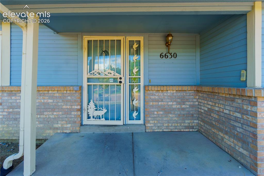 Image 4 of 33: Covered front porch featuring a decorative security screen door, light blue