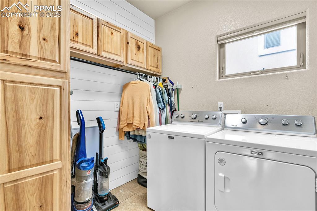 Image 19 of 29: Laundry area with washer and clothes dryer, cabinet space, and a textured w