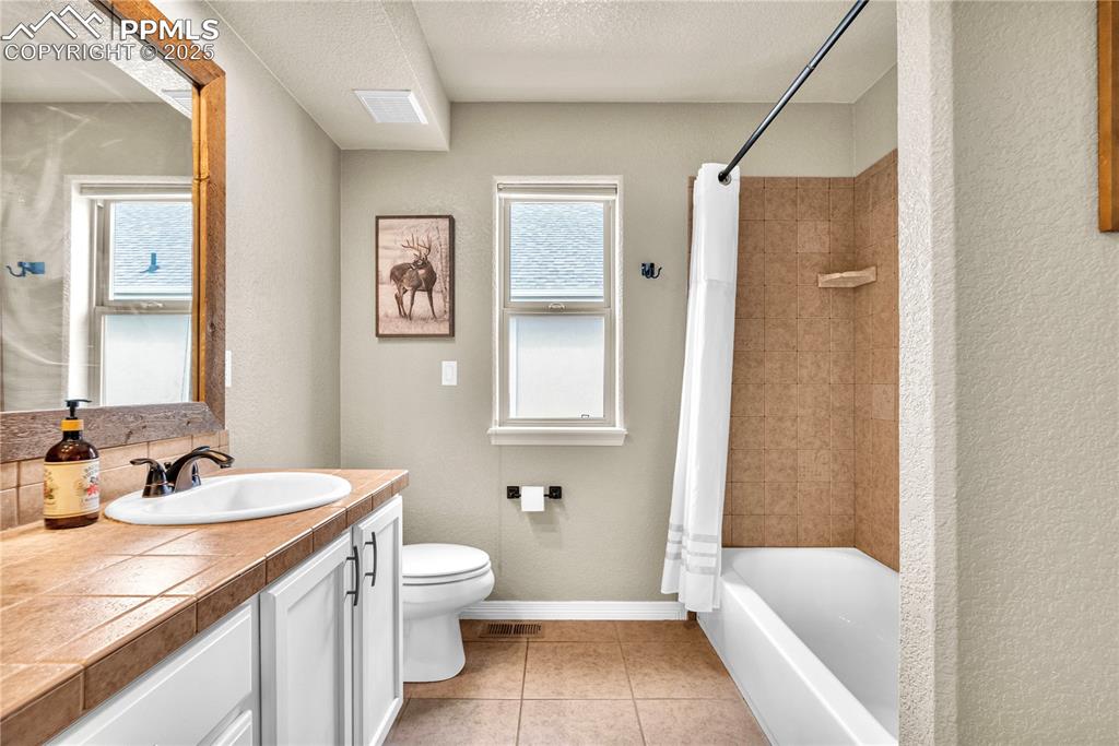 Image 22 of 29: Full bath with vanity, a textured wall, a textured ceiling, shower / tub co