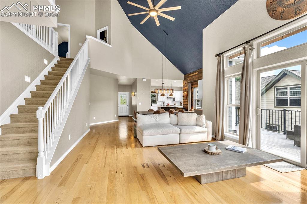 Image 6 of 29: Living area featuring light wood-type flooring, ceiling fan, high vaulted c