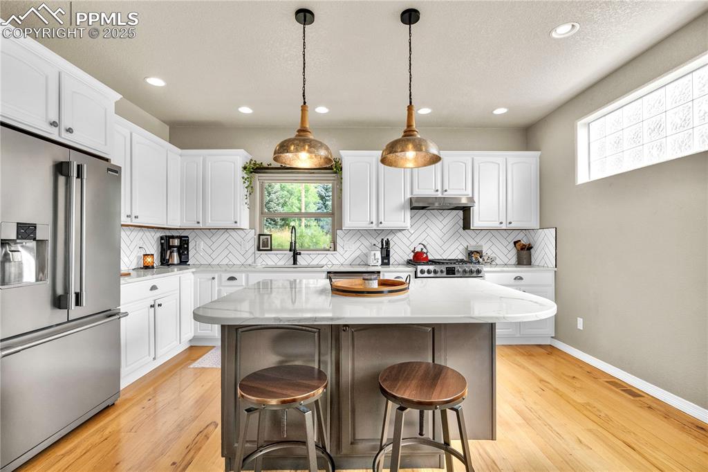 Image 7 of 29: Kitchen with high quality fridge, light wood-style flooring, a breakfast ba