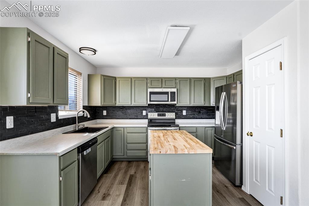 Image 10 of 25: Kitchen featuring appliances with stainless steel finishes, decorative back