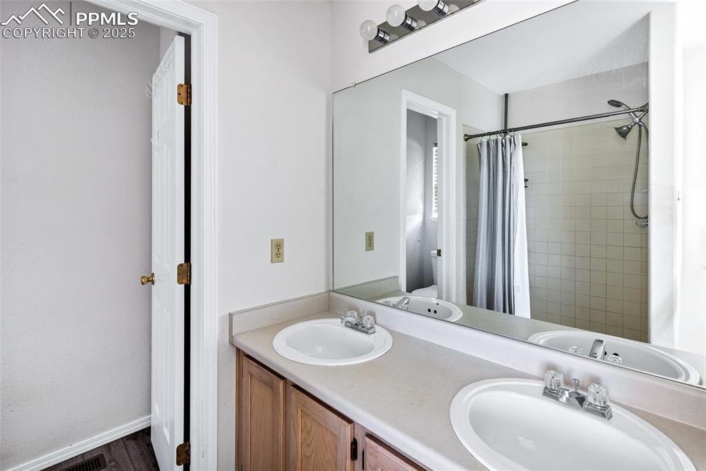 Image 16 of 25: Bathroom featuring tiled shower and double vanity
