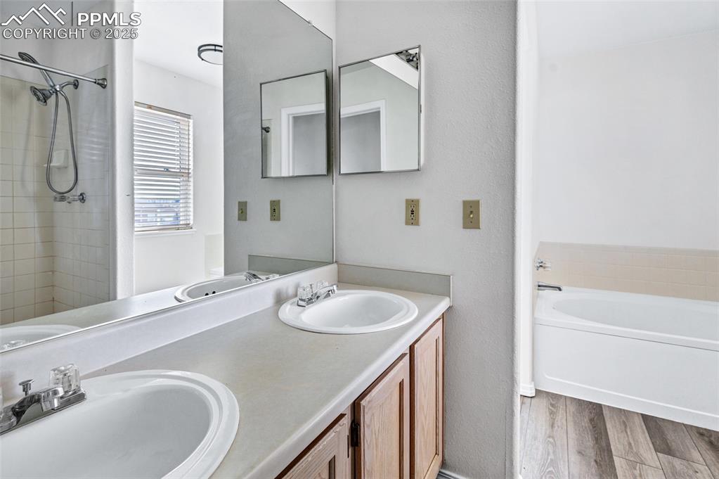 Image 17 of 25: Bathroom featuring a garden tub, double vanity, light wood-style floors, an