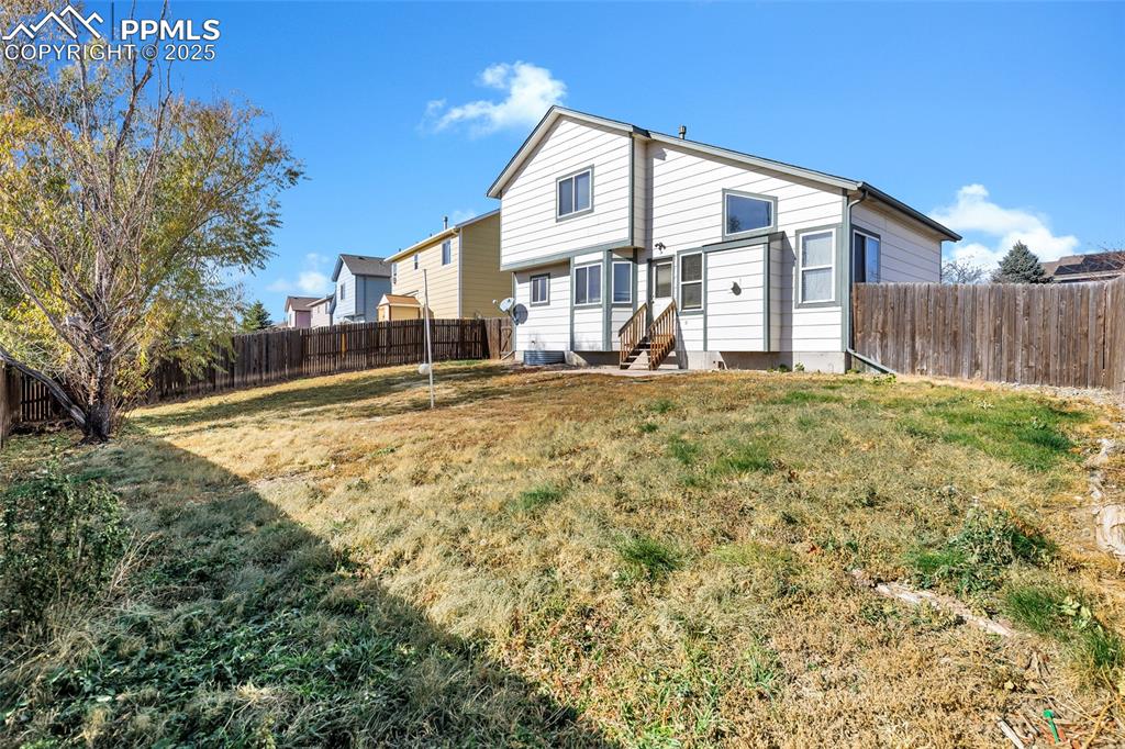 Image 23 of 25: Rear view of property with a fenced backyard and entry steps