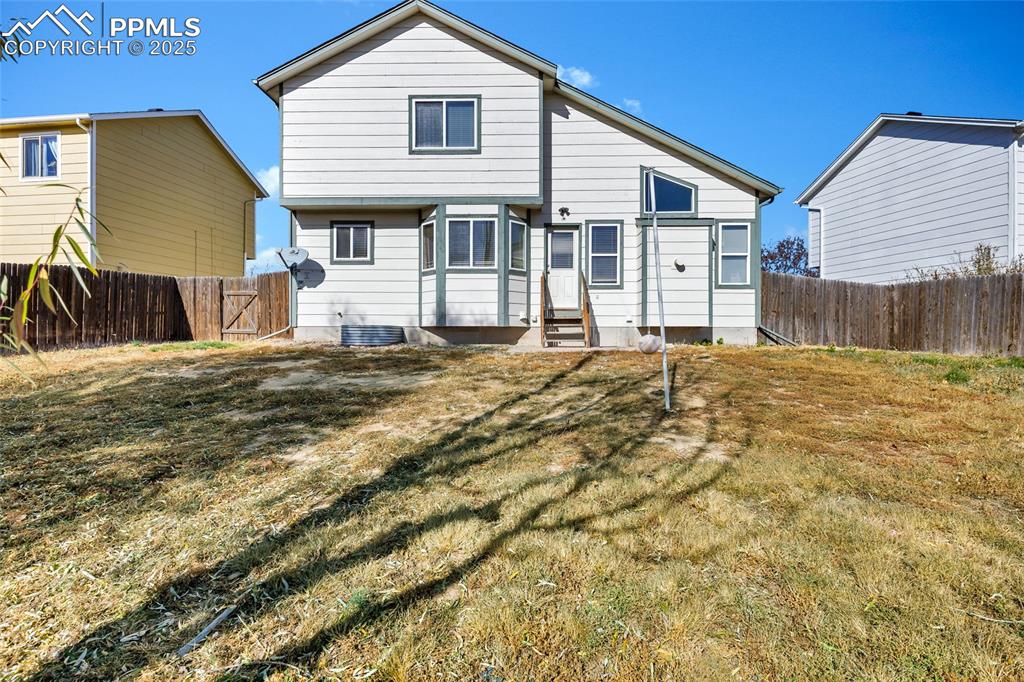 Image 24 of 25: Rear view of house with a fenced backyard and entry steps