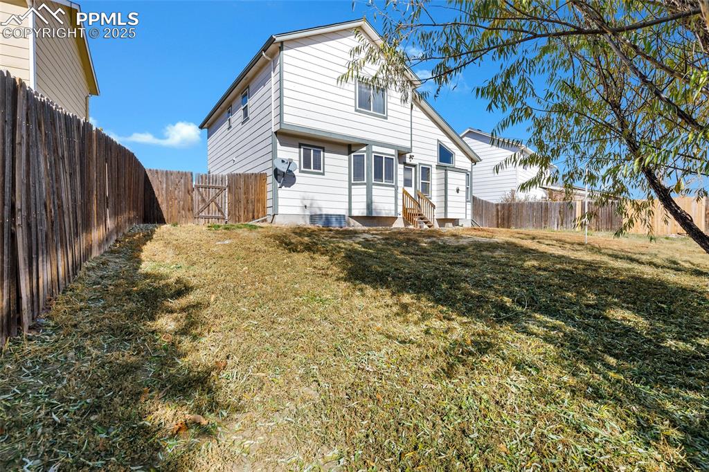 Image 25 of 25: Rear view of house featuring a fenced backyard and entry steps
