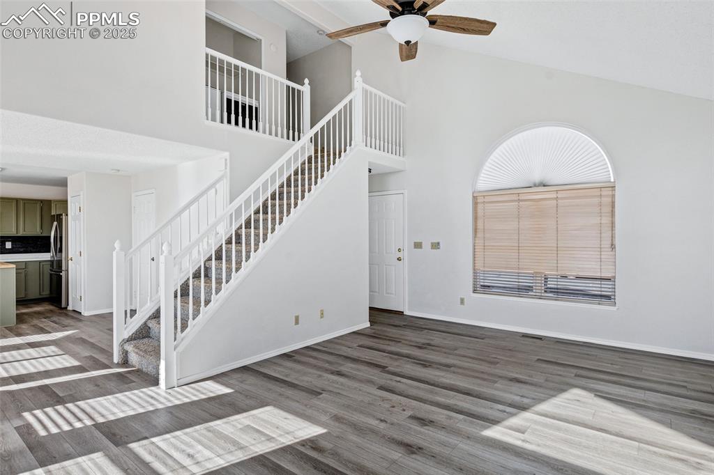 Image 6 of 25: Unfurnished living room with high vaulted ceiling, dark wood-type flooring,