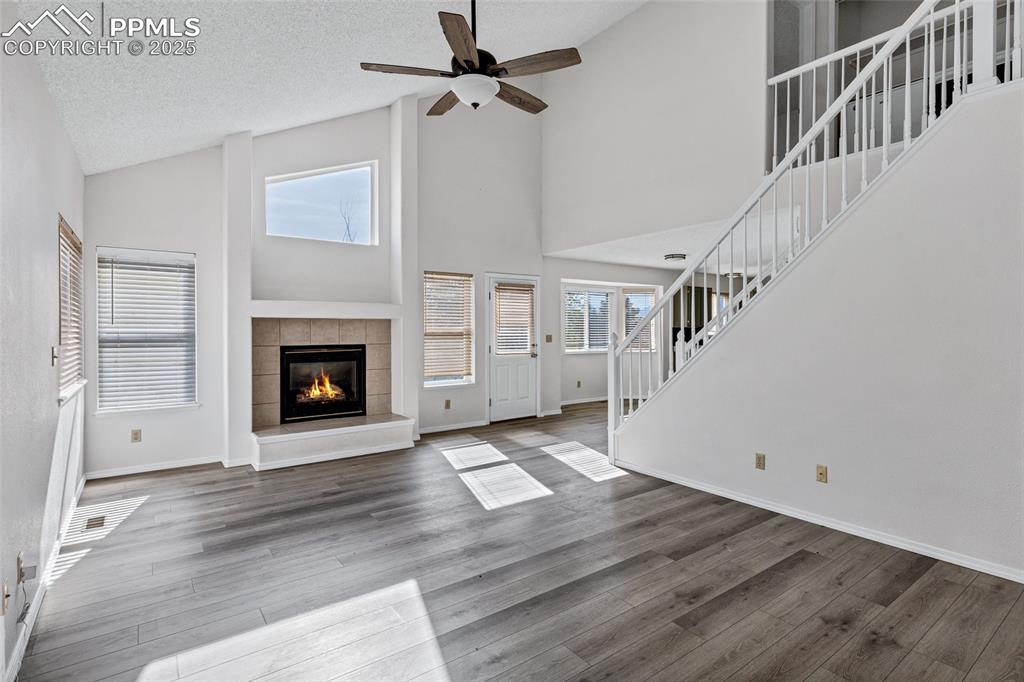 Image 7 of 25: Unfurnished living room with high vaulted ceiling, stairway, wood finished 