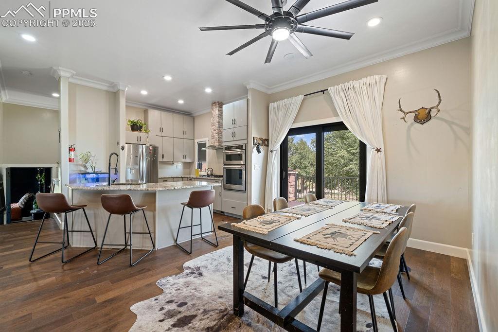 Image 13 of 50: Dining space with crown molding, dark wood-style flooring, a ceiling fan, a