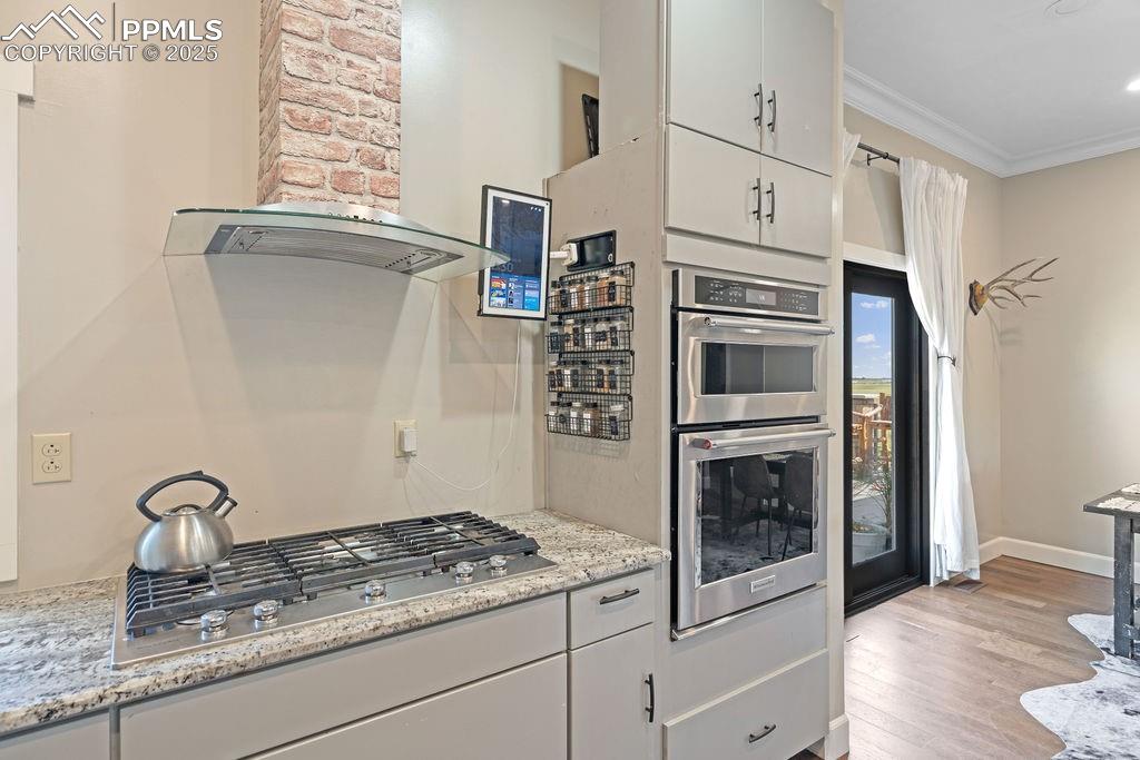 Image 14 of 50: Kitchen featuring wall chimney exhaust hood, white cabinets, stainless stee
