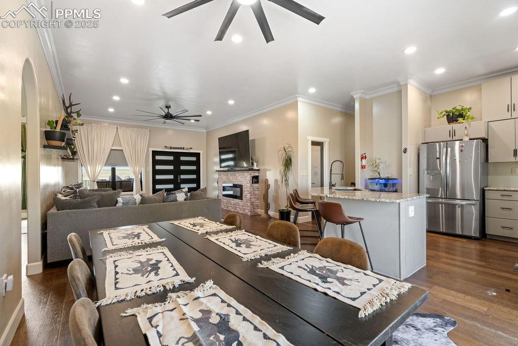 Image 14 of 50: Dining area featuring dark wood-style flooring, ornamental molding, a brick