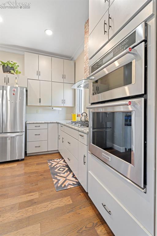 Image 15 of 50: Kitchen with appliances with stainless steel finishes, light wood-style flo