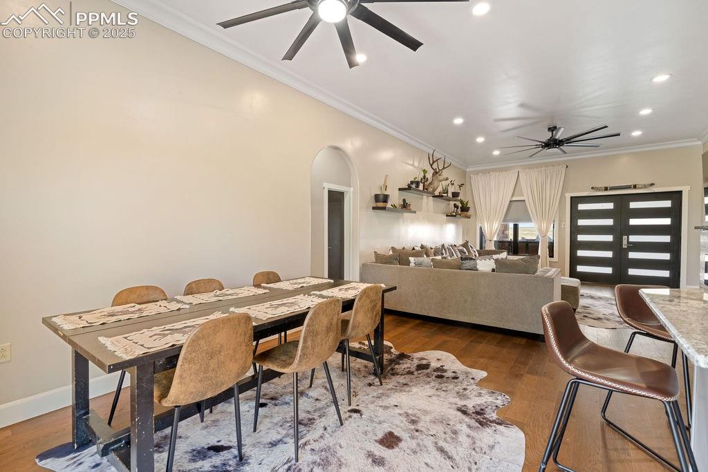 Image 16 of 50: Dining room featuring crown molding, arched walkways, dark wood finished fl