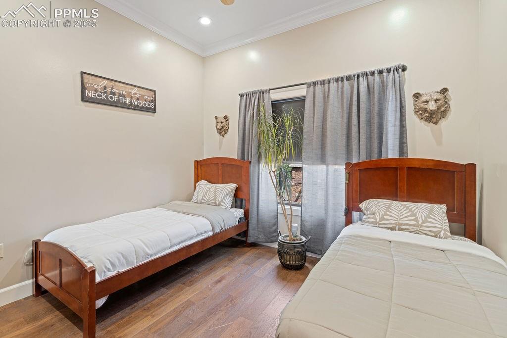 Image 25 of 50: Bedroom featuring ornamental molding, dark wood-style floors, and recessed