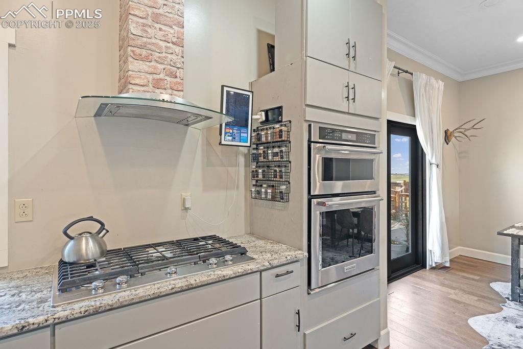Image 3 of 50: Kitchen featuring wall chimney exhaust hood, white cabinets, stainless stee