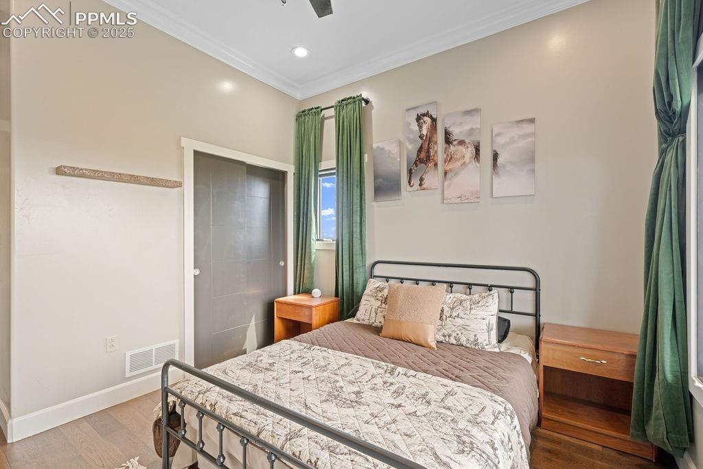 Image 36 of 50: Bedroom with ornamental molding, wood finished floors, ceiling fan, and rec