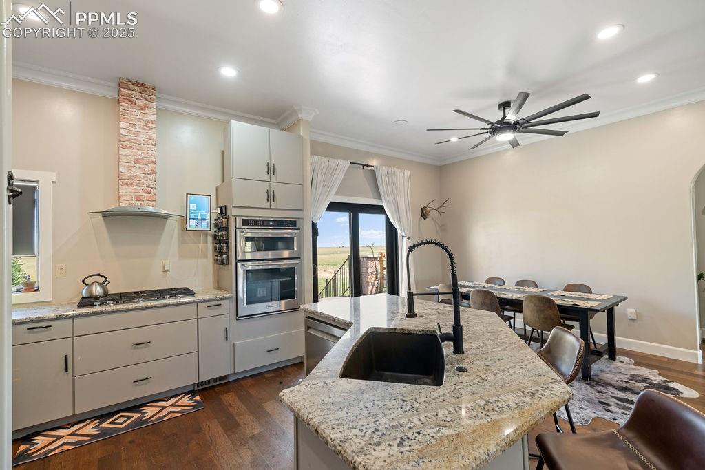 Image 4 of 50: Kitchen with dark wood finished floors, crown molding, a center island with